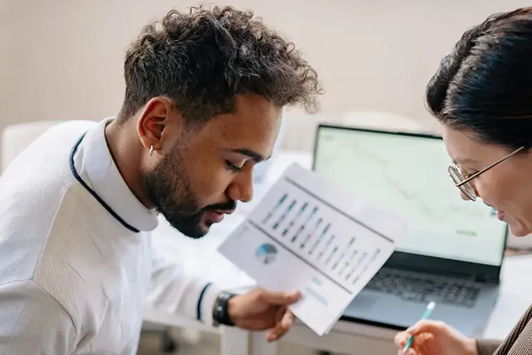 Two office workers chat over a laptop