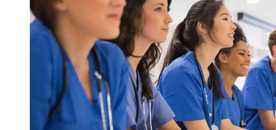 A line of seated doctors in blue uniform are being briefed.