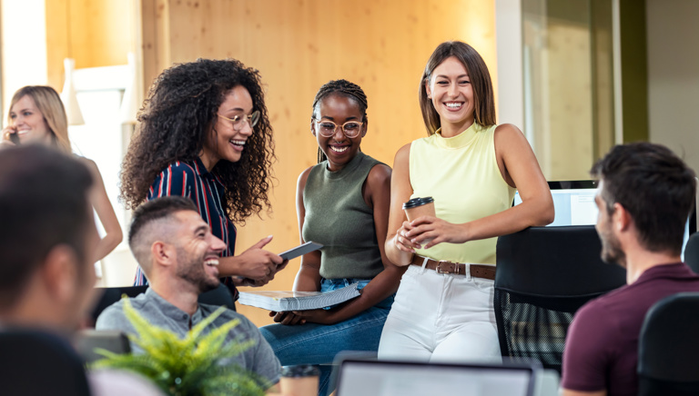 A mixed group of young people smiling and working in an office setting