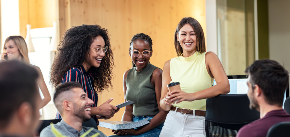 A mixed group of young people smiling and working in an office setting