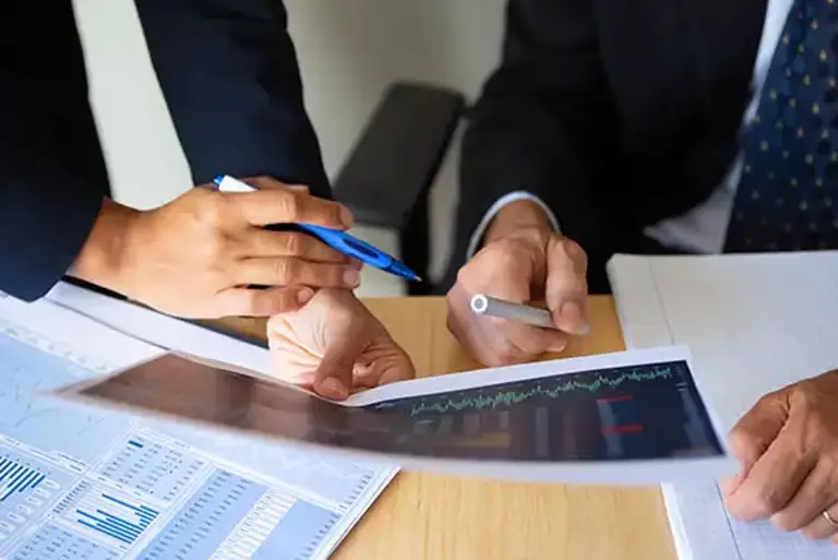 Close up of the hands of two office workers holding print outs of charts