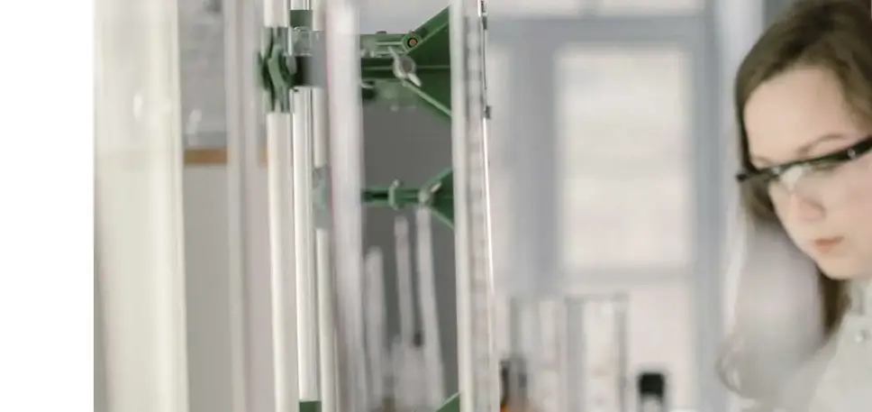 A pair of scientists stand to the side while they examine long titration tubes