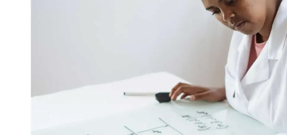 Scientist looking at large sheet on a desk which features mathematical equations