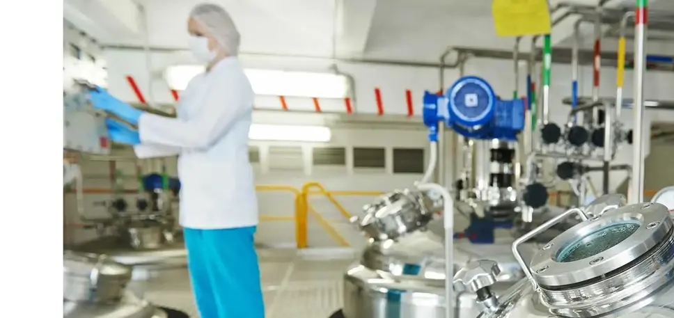 Scientist in the background, with huge stainless steel vats in the foreground 