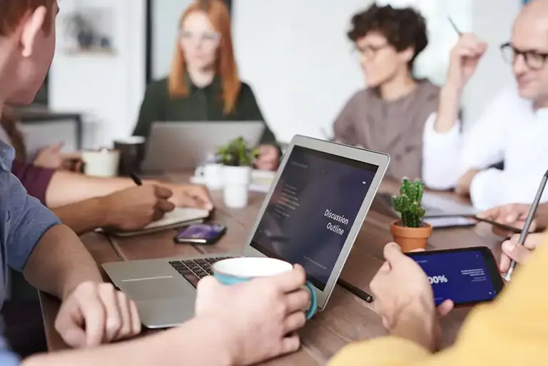 Team of office workers sat around a large conference table having a meeting